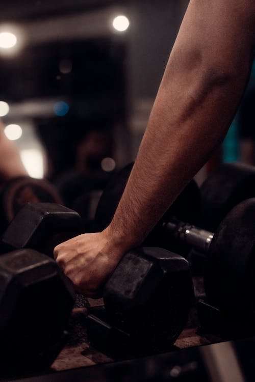 Close-up of a hand gripping a dumbbell in a gym, illustrating heavy resistance training