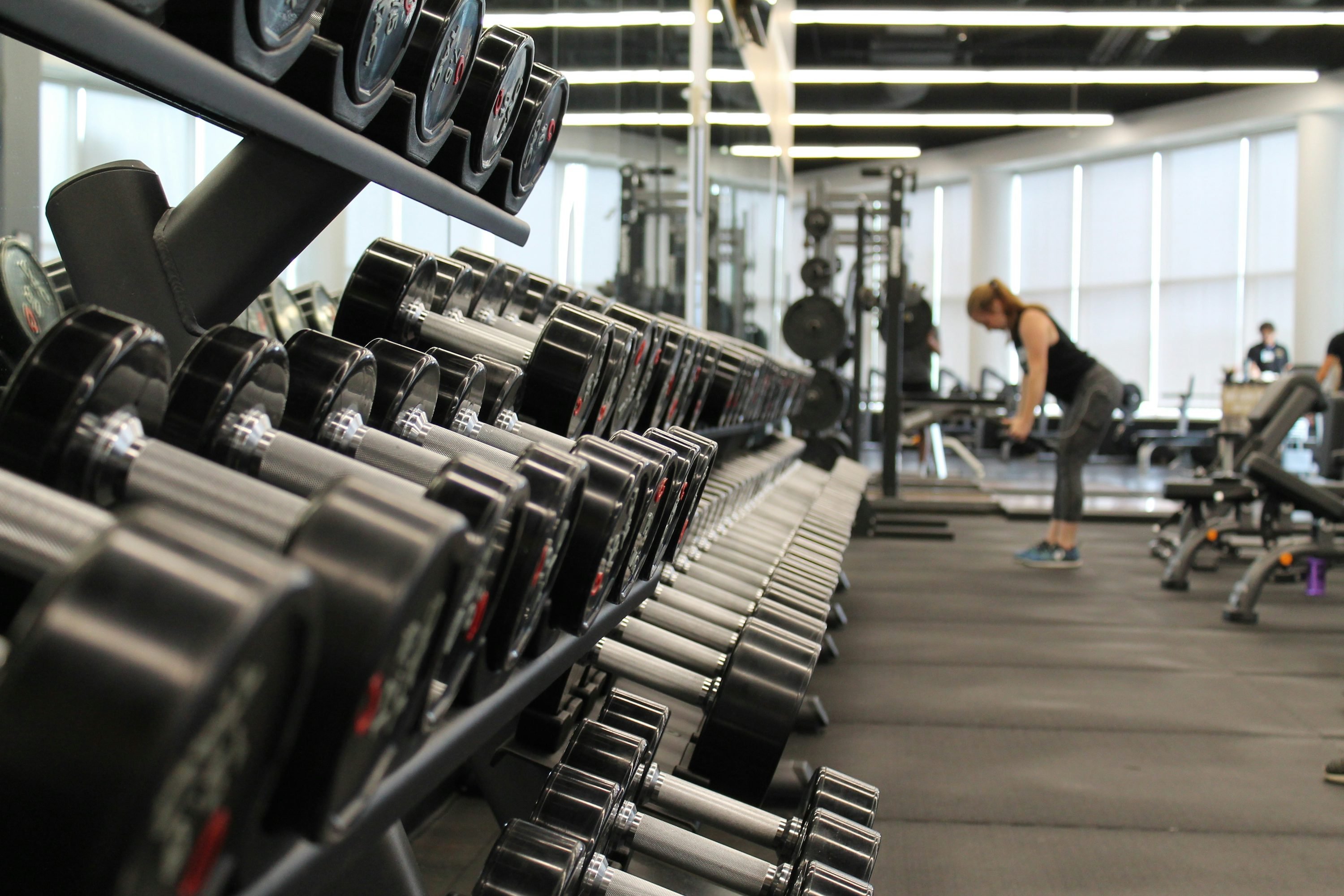Realistic photograph of a person performing a full-body strength training exercise in a gym, illustrating a basic musculation workout