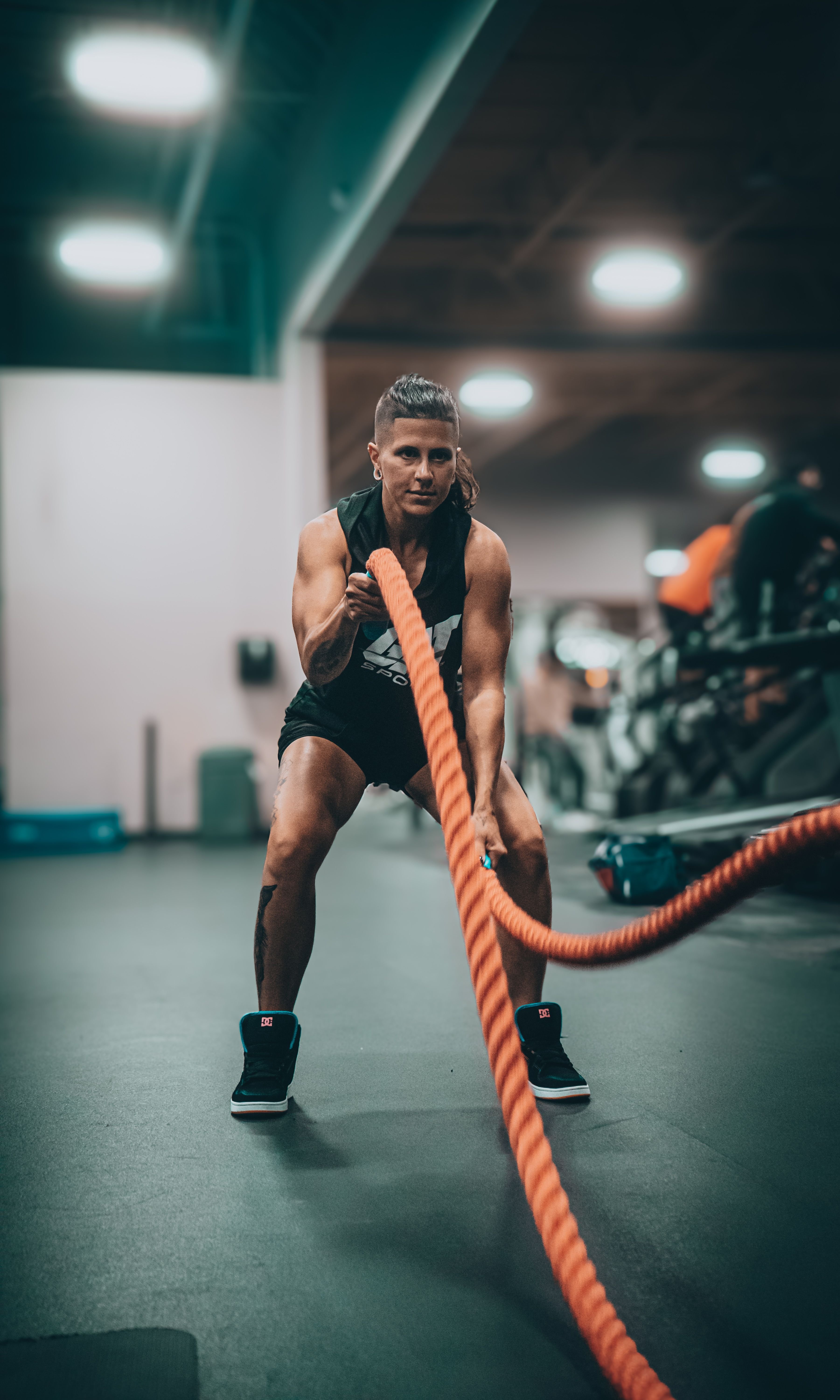 Athlète en mouvement utilisant une corde à tirage en salle de sport, entraînement dynamique et effort musculaire visibles. Programme full body ou split à l’affiche.