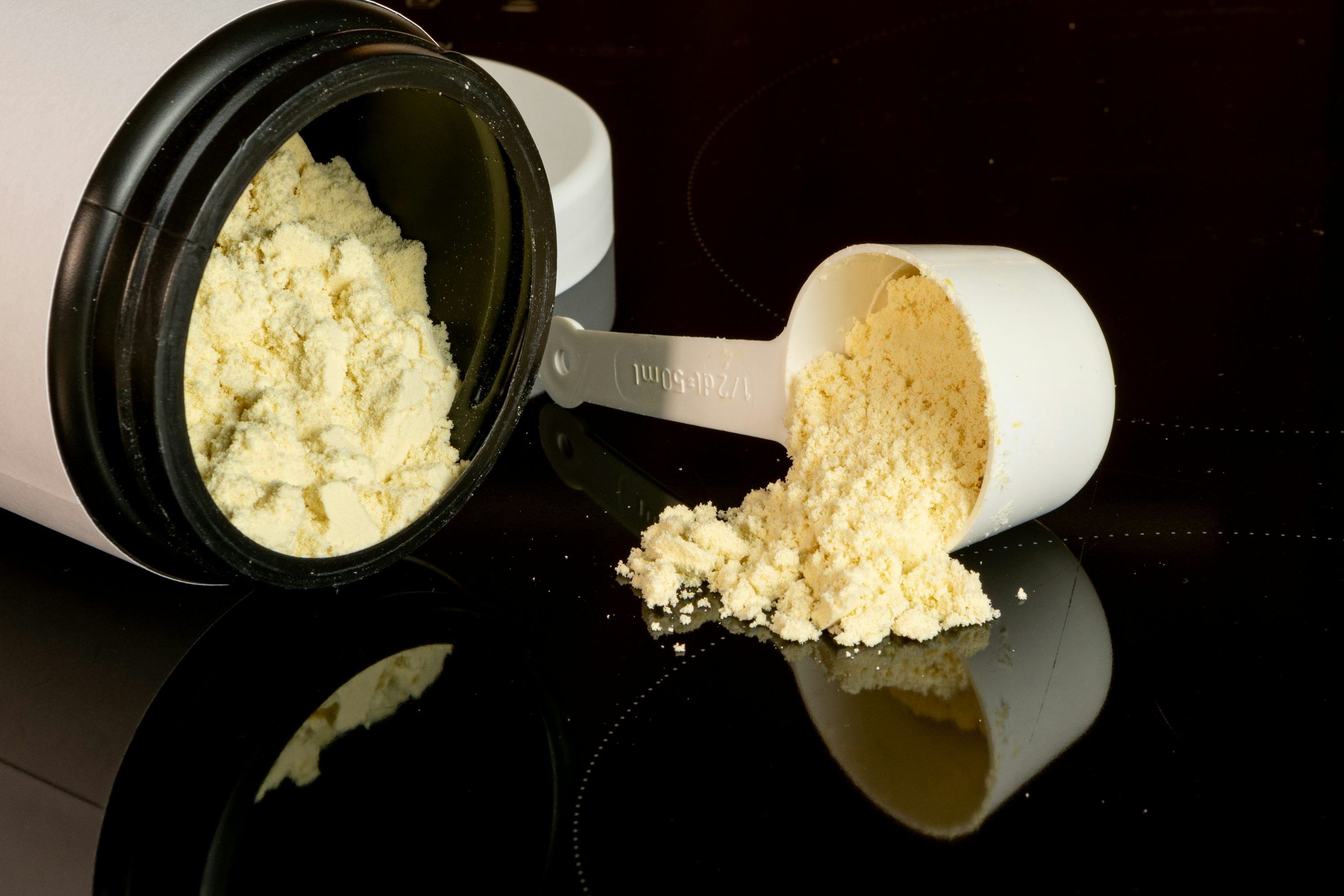 Photo of assorted protein powder containers and scoops, illustrating different types of protein supplements.