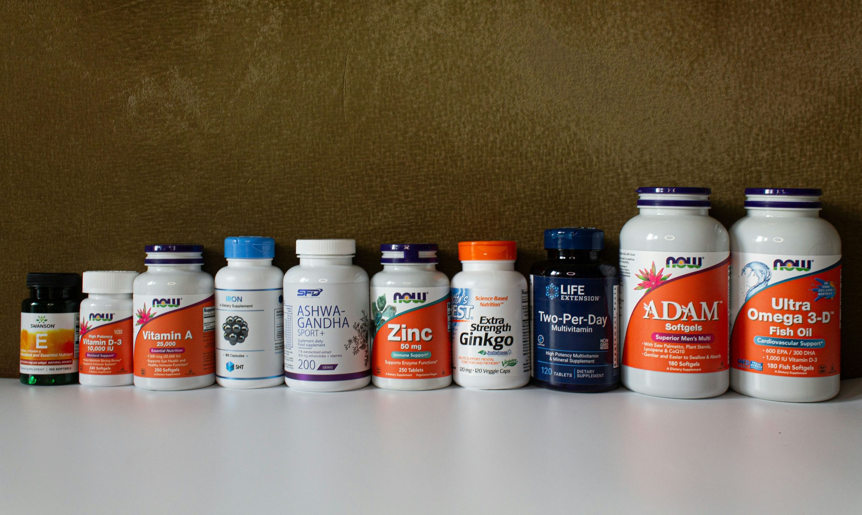 A row of assorted supplement bottles on a white surface, detailing vitamins and minerals for bodybuilding. Essential minerals for bodybuild highlighted by the lineup.