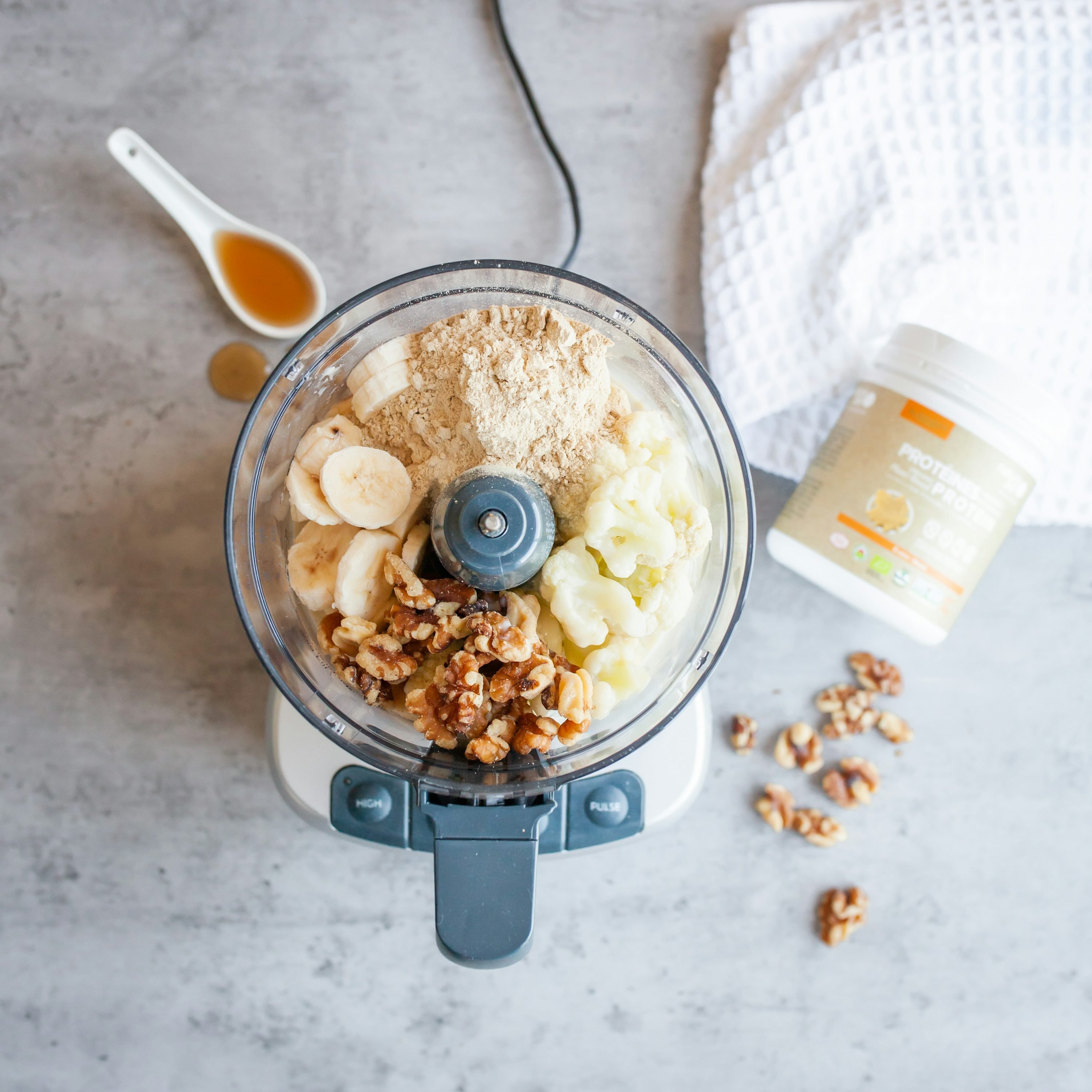 Smoothie-friendly ingredients in a blender: bananas, oats, and walnuts ready to blend with protein powder, showcasing how to use protein powder in recipes.
